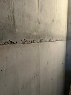 Betonierfuge mit krümelig ausgebrochener Kante, darüber eine raue Zone, darunter glatter Beton