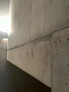 Treppenwange mit schräger Fuge und glatter Fläche, rechts oben ein heller Wandabschnitt, unten Dunkelheit
