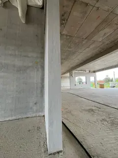 Helle, glatte Betonstütze im Rohbau unter einer Plattendecke, links eine Sichtbetonwand