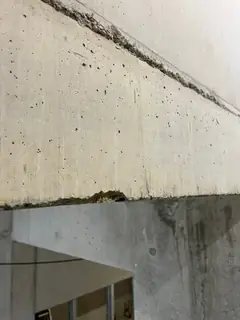 Betonkante an einem Unterzug mit kleinen Ausbrüchen am unteren Rand und schräger Fuge oben
