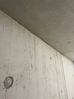 Ecke zwischen Betonwand und Decke mit schräger Kante, links unten ein kleiner Ankerkonus