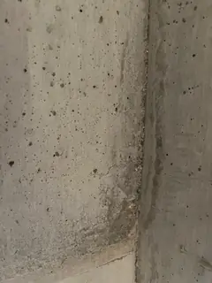 Innenkante zweier Betonflächen mit rauem, dunklem Streifen und zahlreichen Lunkern in der linken Fläche