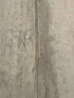 Senkrechte Fuge mit Versatz in der Mitte, daneben fleckige, teils rau abgesandete Betonflächen