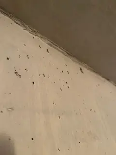 Schräg verlaufende Deckenkante über einer beigen Betonfläche mit verstreuten kleinen Lunkern