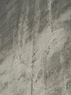 Betonfläche mit starken, dunklen und hellen Flecken und einer senkrechten feinen Fuge in der Mitte