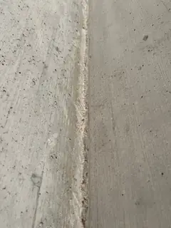 Senkrechte Betonkante mit schmalem, ausgebrochenem Streifen, links und rechts glatte Flächen