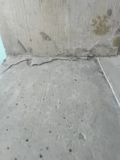 Anschluss einer Betonplatte an eine Wand mit feinem Riss entlang der Kante und vielen kleinen Lunkern