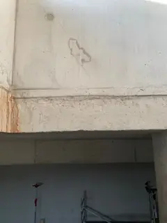 Betonkante über einer Öffnung mit feinem Riss, einem rostfarbenen Fleck an der Ecke und einer Spur