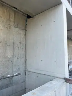 Betonwand und Betonbrüstung an einem Außenbereich, links ein Sichtbetonabschnitt, rechts eine glatte Platte