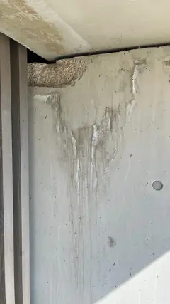 Obere Ecke eines Betonelements unter der Decke mit Ausbruch und hellen Läufern, die nach unten ziehen