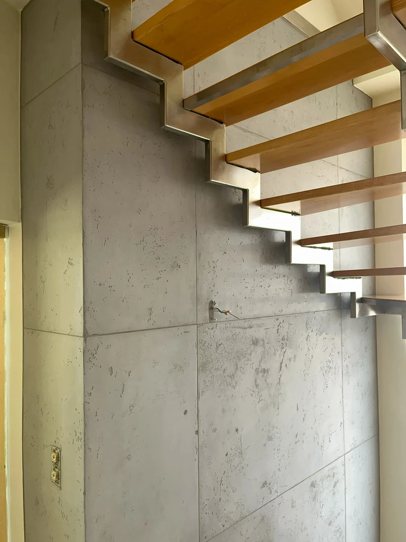 Nahaufnahme Schalbetonoptik an einer Wandecke mit Poren, Lunkern und Plattenstoß neben der Holztreppe