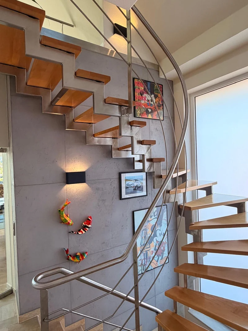 Eingeräumte Treppenwand in Betonoptik mit Wandleuchte, Bildern und bunten Figuren an der Holztreppe, Chemnitz