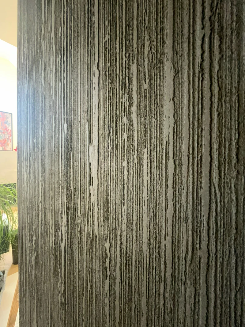 Schwarze Kalkstruktur mit senkrechten Rillen schräg von der Seite fotografiert, Designwand im Wohnraum, Chemnitz