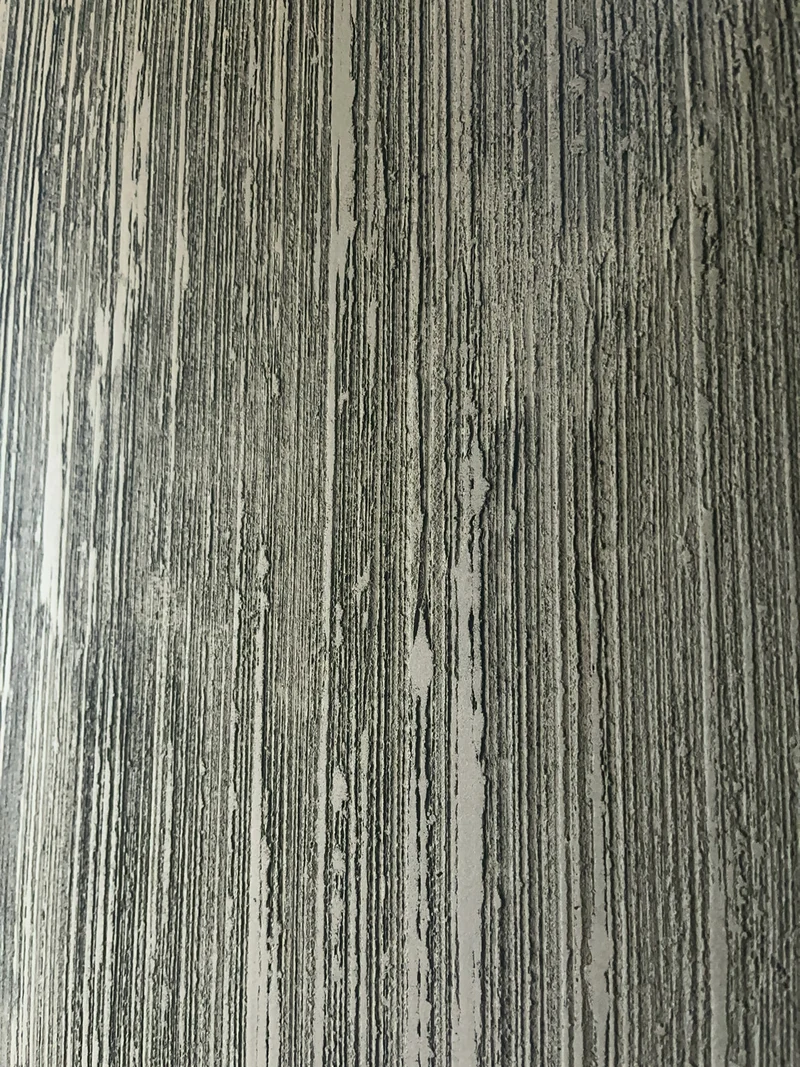 Schmaler Ausschnitt einer Designwand schwarz mit eng stehenden Rillen und feinen Graten aus Kalk