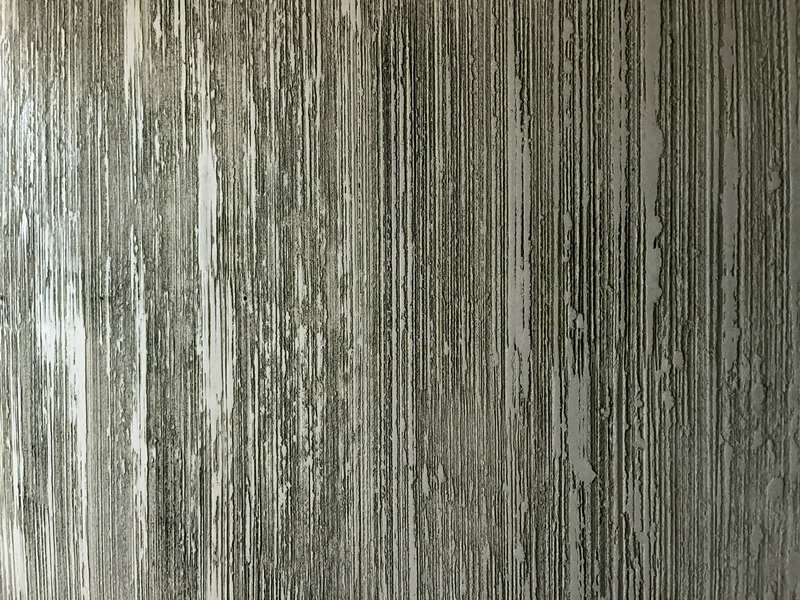 Feine Abrisse zwischen senkrechten Rillen in einer schwarzen Kalkwand, Detail der kreativen Wandgestaltung