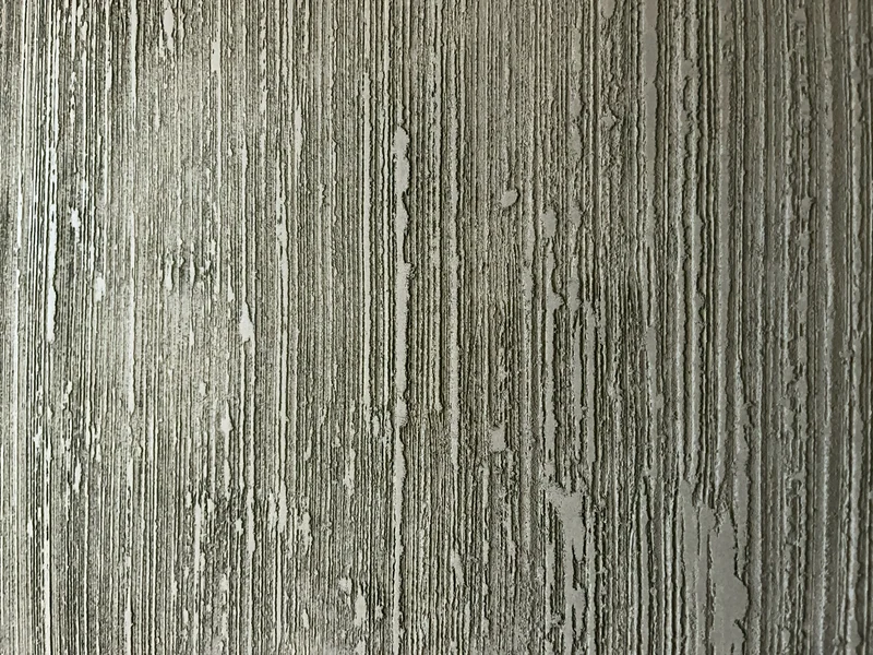 Senkrechte Rillenstruktur aus Kalk bei weichem Licht, kaum Glanz, Detail einer schwarzen Designwand