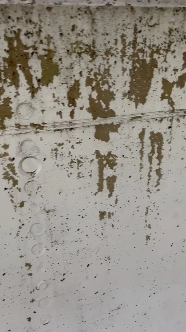 Abblätternde Farbe in Platten auf einer Betonmauer im Außenbereich