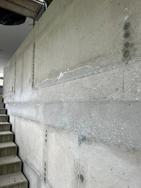 Abgeschliffener Beton mit Schalungskanten und Resten alter Spachtelung, aus der Nähe