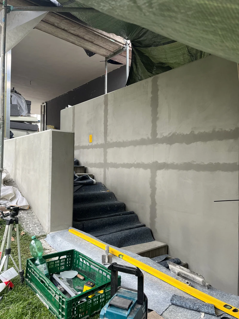 Fugenraster an einer Betonwand mit dunklerer Spachtelmasse vorgespachtelt, daneben ein Linienlaser