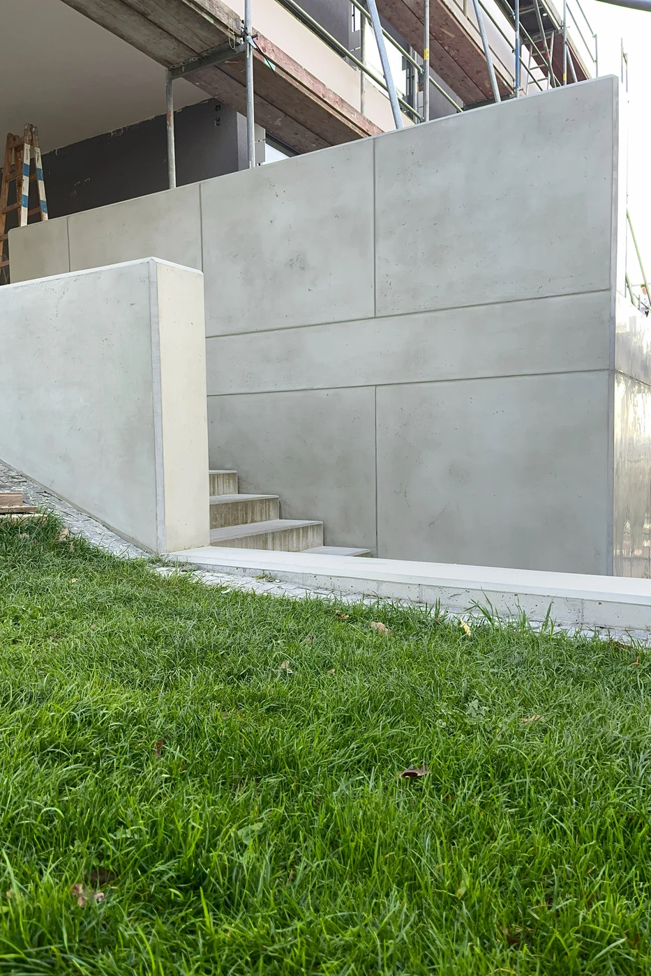 Große Wand in Schalbetonoptik mit Fugenraster, schräg von der Gartenseite fotografiert