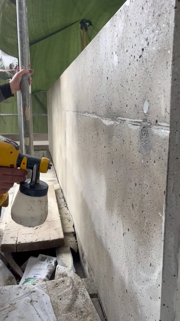 Video: Grundierung wird mit einer Handspritzpistole auf eine geschliffene Betonmauer gesprüht