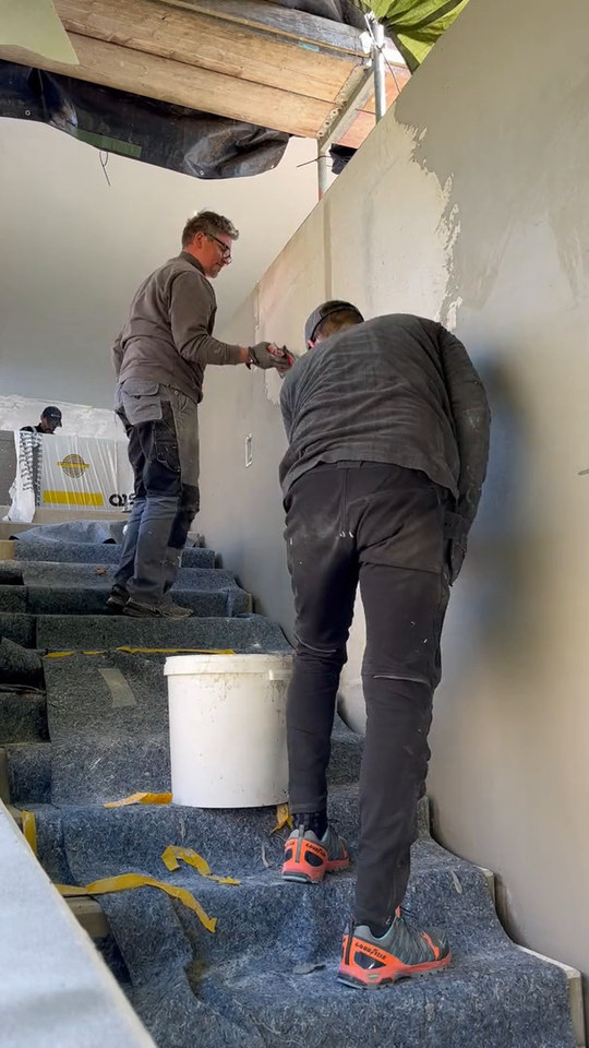Video: Grundspachtel wird im Zeitraffer auf das Gewebe einer Betonwand an der Treppe gespachtelt