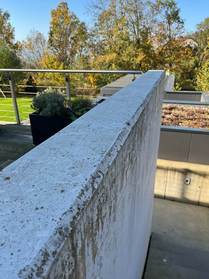 Verwitterte Mauerkrone mit abgeplatzter Farbe an einer Terrasse, vor der Sanierung
