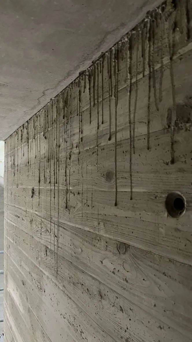 Betonnasen und Betonläufer: Dunkle Betonlaufspuren an der Wand unterhalb der Decke vor der Reinigung.
