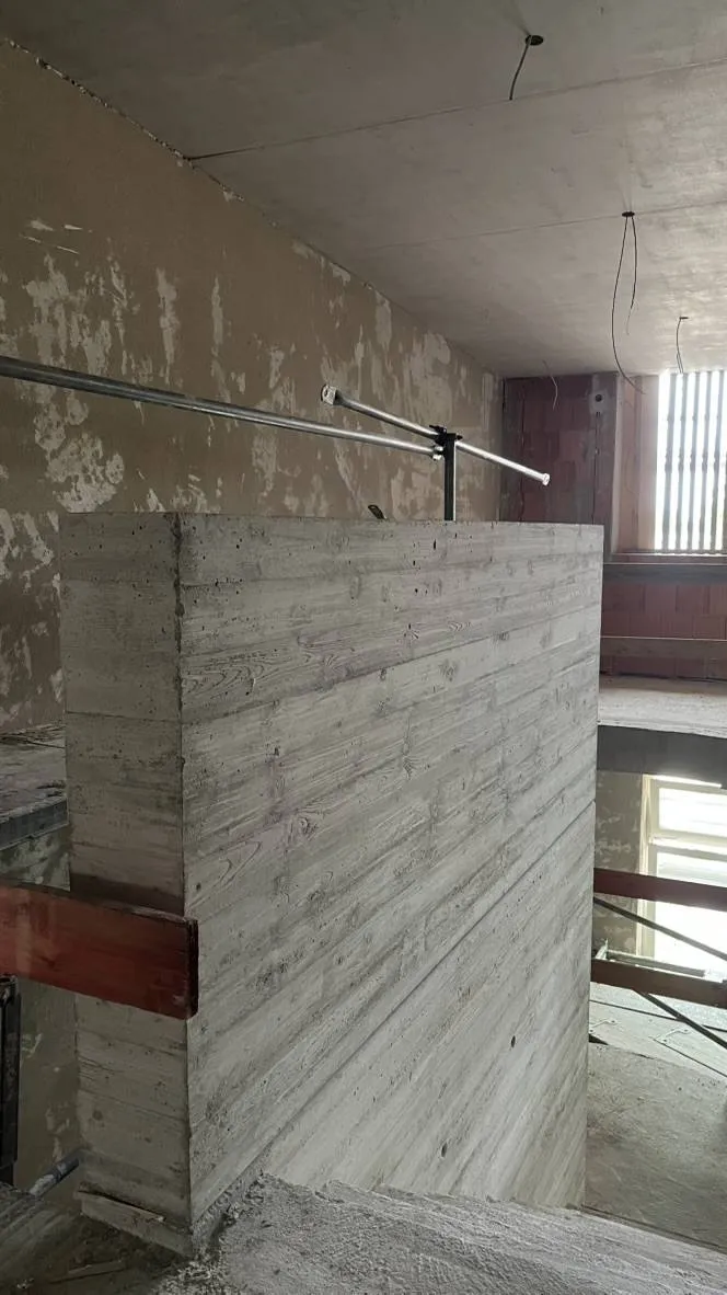 Wandkopf im Treppenhaus: Ergebnis. Sichtbetonwand mit durchgehender Holzschalungsstruktur.