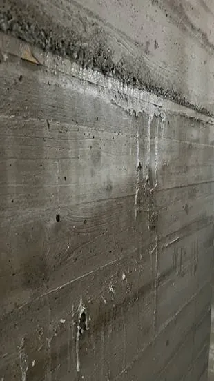 Wand mit Zementläufen und Verschmutzungen vor der Reinigung.