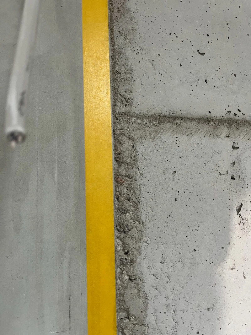Detail der vorbereiteten Betonkante: links glattes Betonfertigteil, rechts Ortbeton aus Recyclingbeton mit Poren