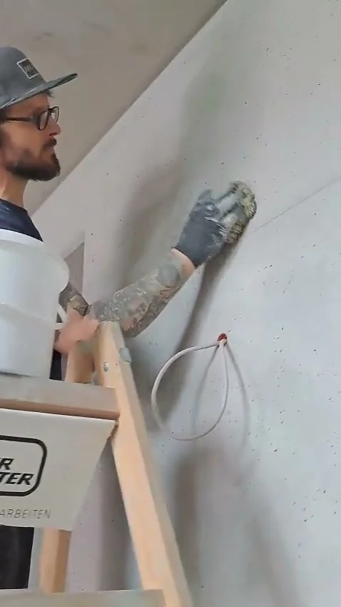 Video: Handwerker auf der Leiter retuschiert die Ortbetonwand aus Recyclingbeton mit dem Naturschwamm