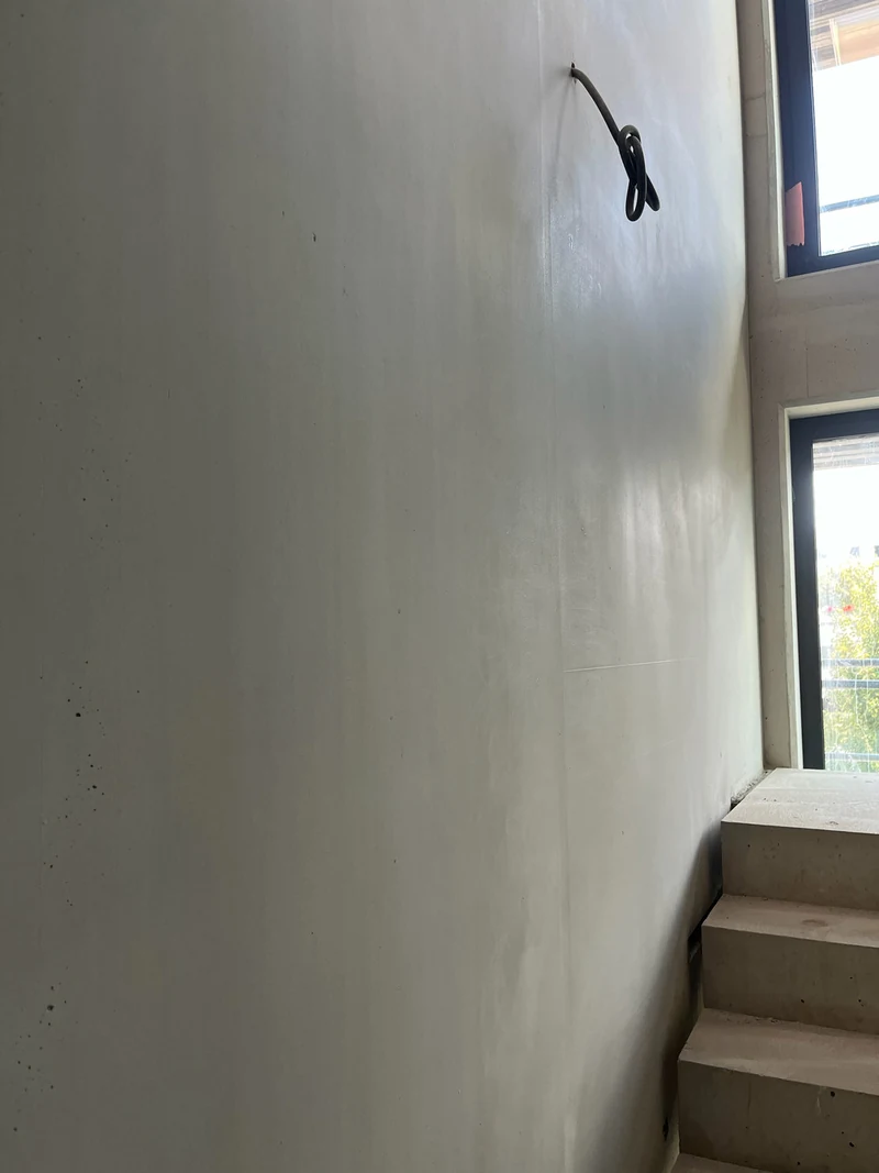 Nachher: hohe homogene Betonfertigteilwand über den Treppenstufen mit Fenster rechts, Stand Rohbauphase