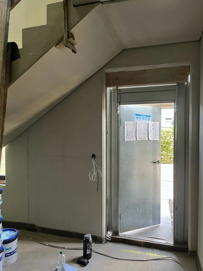Nachher: Ortbetonwand im Eingangsbereich des Erdgeschosses mit Treppenlauf darüber, Stand Rohbauphase