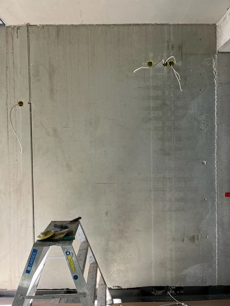 Vorher: Betonfertigteilwand im Erdgeschoss mit Betonläufern, durchgezeichneter Bewehrung und Abrieben