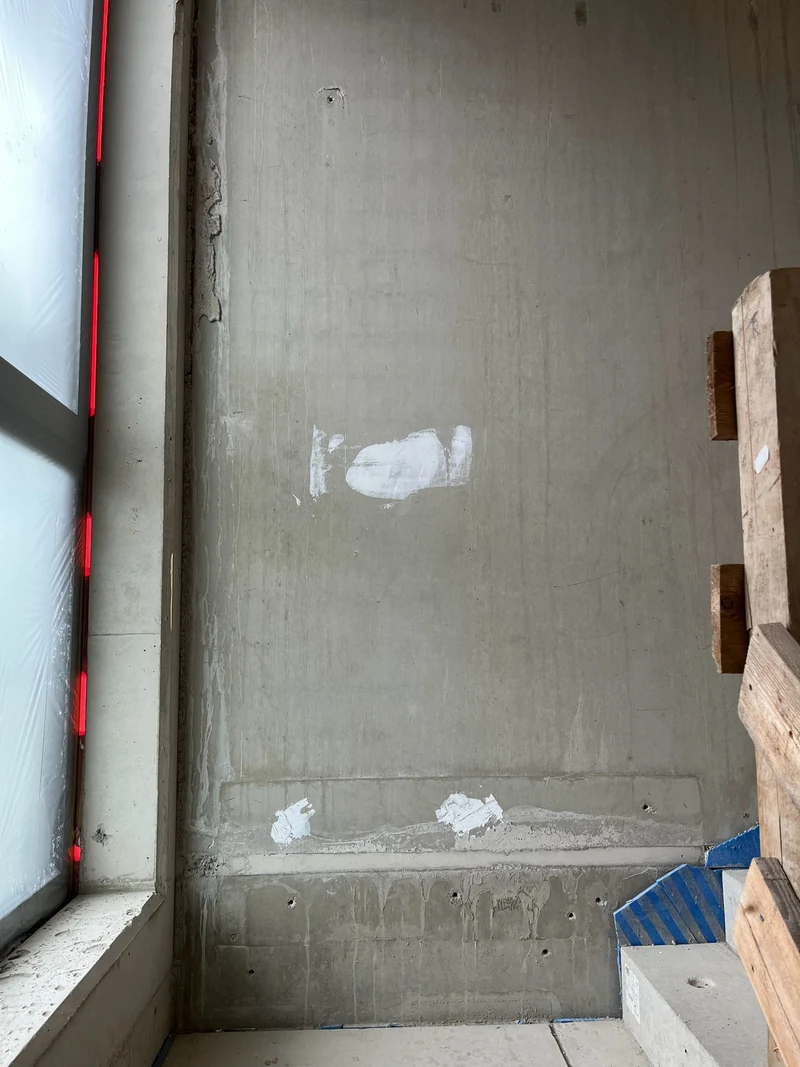 Vorher: Betonfertigteilwand am zweiten Podest mit zugelaufener Fuge, Schmutz und Farbflecken, Fensterband links