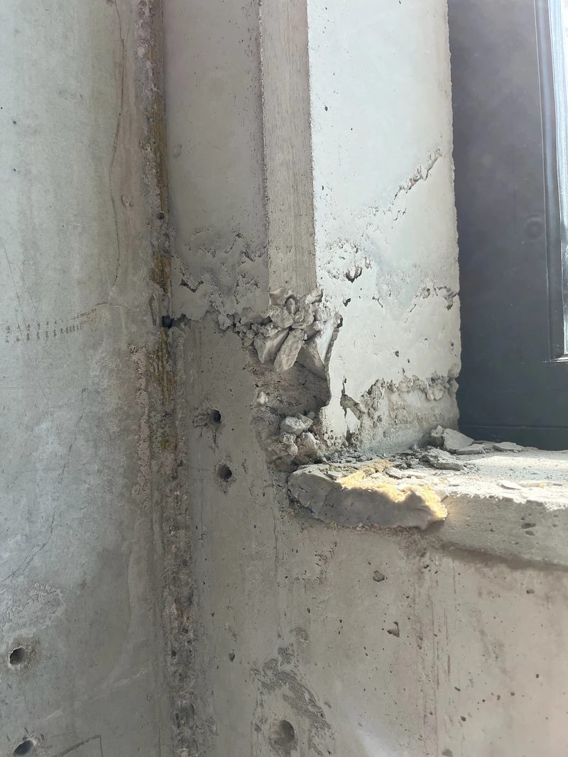 Vorher: Fensterkonsole im Treppenhaus mit ausgebrochenen Stellen, Bohrlöchern und größeren Beschädigungen am Beton