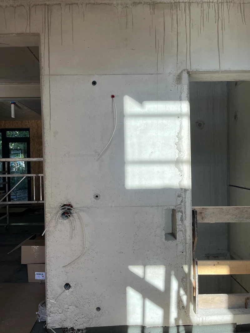 Vorher: Ortbetonwand am Aufzug im Erdgeschoss mit Verschmutzungen, Bohrlöchern und Spuren aus der Bauzeit