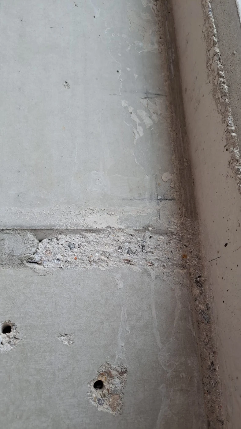 Vorher: waagerechte Arbeitsfuge zwischen zwei Betonfertigteilen, mit Beton zugelaufen, Bohrlöcher darunter
