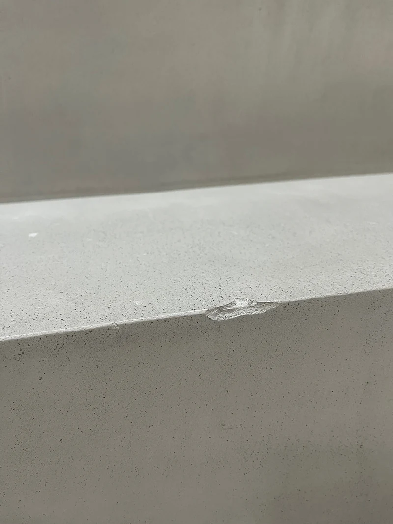 Abplatzung an der Stufenkante einer Treppe aus Beton Ciré, Schaden durch Spiegelscherben, vor der Reparatur