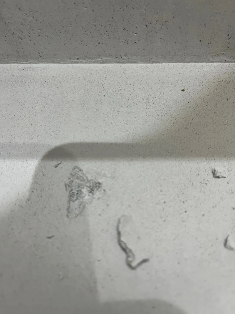 Nahaufnahme einer Trittstufe aus Beton Ciré mit Einschlägen und Kratzern durch Spiegelscherben vor der Reparatur