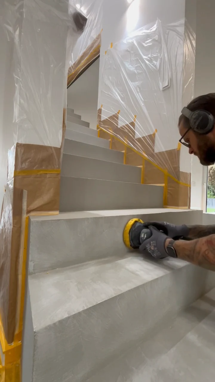 Video: Auf der Treppe kniend wird die Spachtellage mit dem Rotationsschleifer geschliffen, Knie und Maschine im Bild