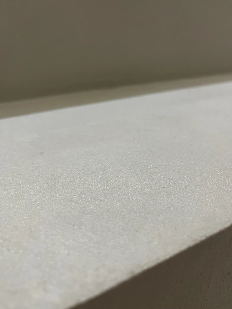 Nahaufnahme der gespachtelten Oberfläche aus Beton Ciré an einer Stufenkante, feine Struktur nach dem Spachteln