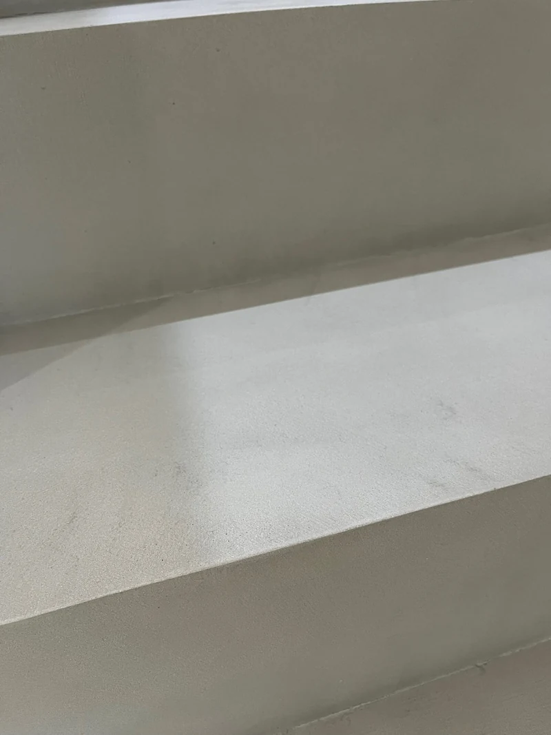 Detail einer fertigen Stufenkante aus Beton Ciré nach der Reparatur, Tritt und Setzstufe im Streiflicht
