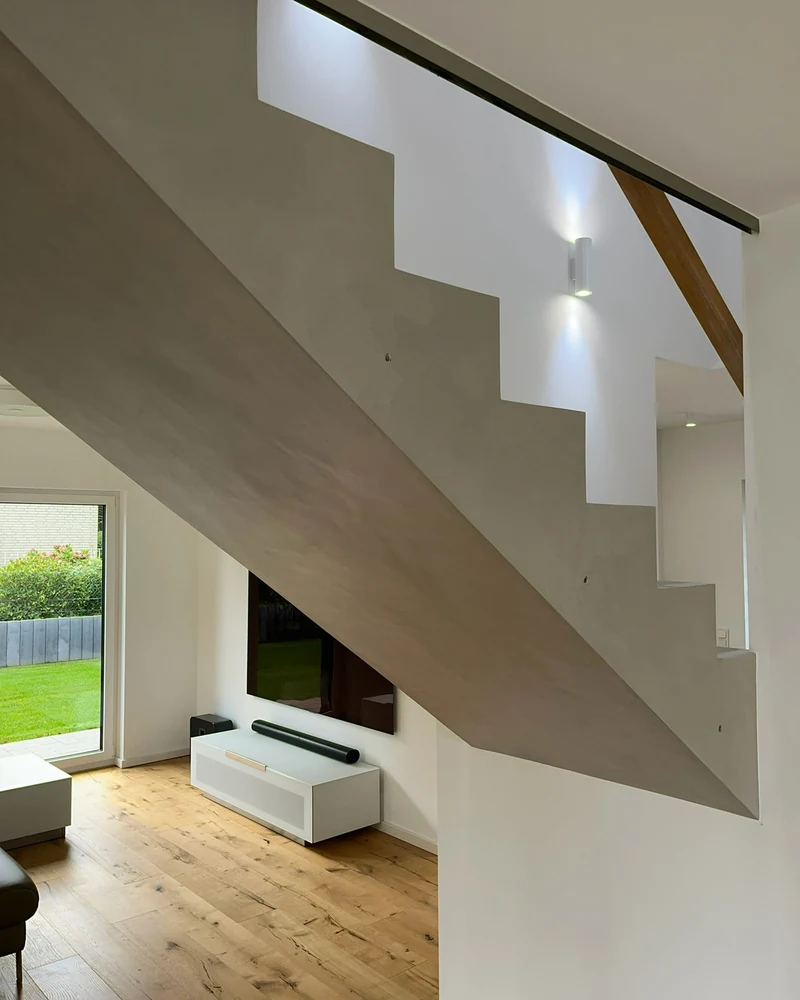 Wange und Untersicht der reparierten Treppe mit Glasgeländer, dahinter der Wohnraum mit Terrassentür