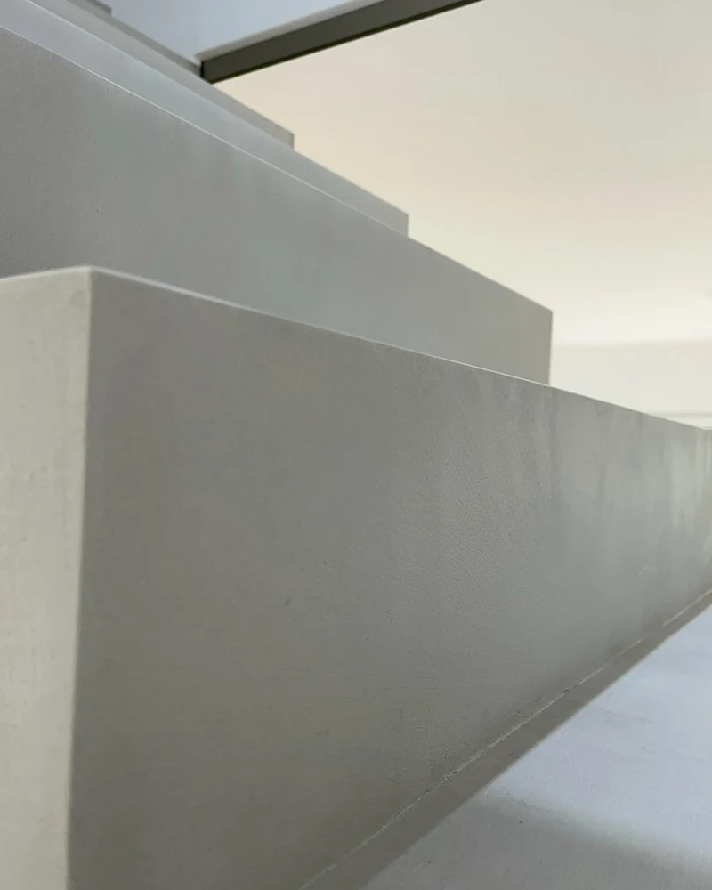 Wangenkante der beschichteten Treppe ganz nah von unten, gleichmäßige Oberfläche aus Beton Ciré