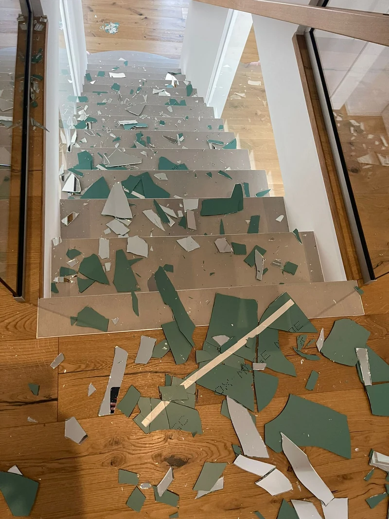 Scherben eines heruntergefallenen Wandspiegels liegen auf der Treppe aus Beton Ciré, Ursache der Reparatur in Marl