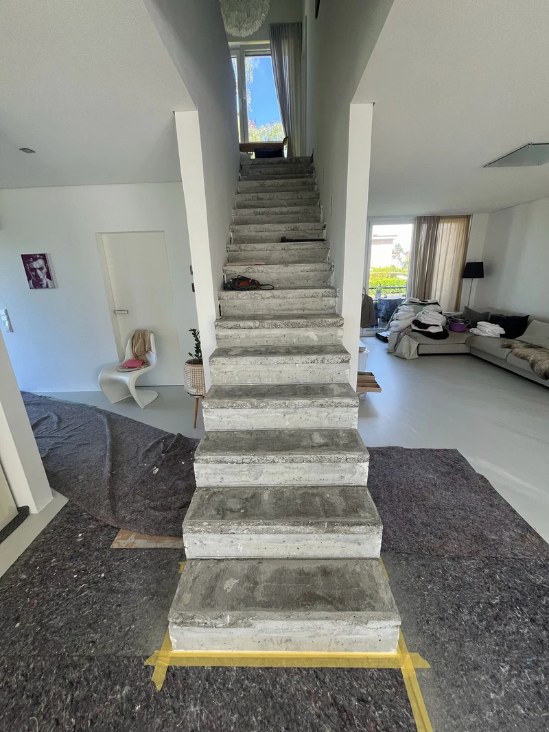 Treppe frontal mit abgedecktem Boden und gelbem Klebeband am Antritt, vorbereitet für die Beschichtung mit Mikrozement