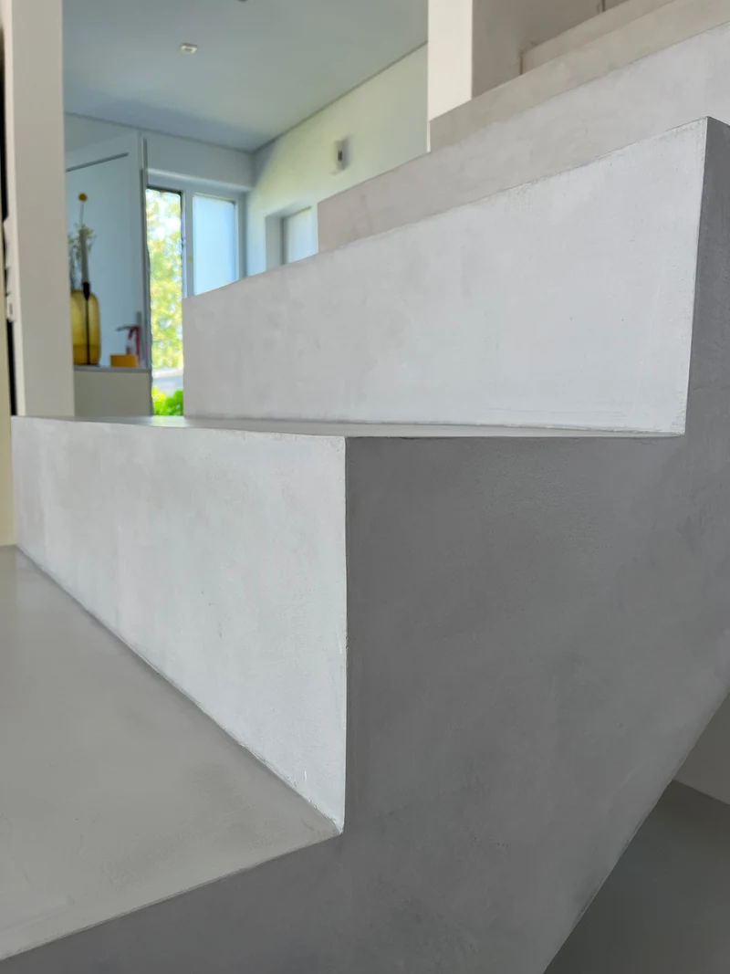 Nachher: Steigung und Flanke der Mikrozement-Treppe ganz nah, ohne Absatz bis in die Ecke, Fenster im Hintergrund