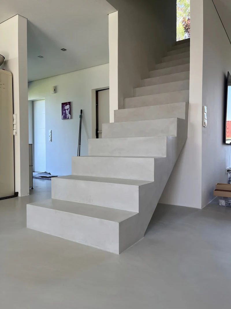 Nachher: Treppe von unten links mit Mikrozement, Tritt, Kante und Flanke laufen in einem Zug, Bild an der Wand